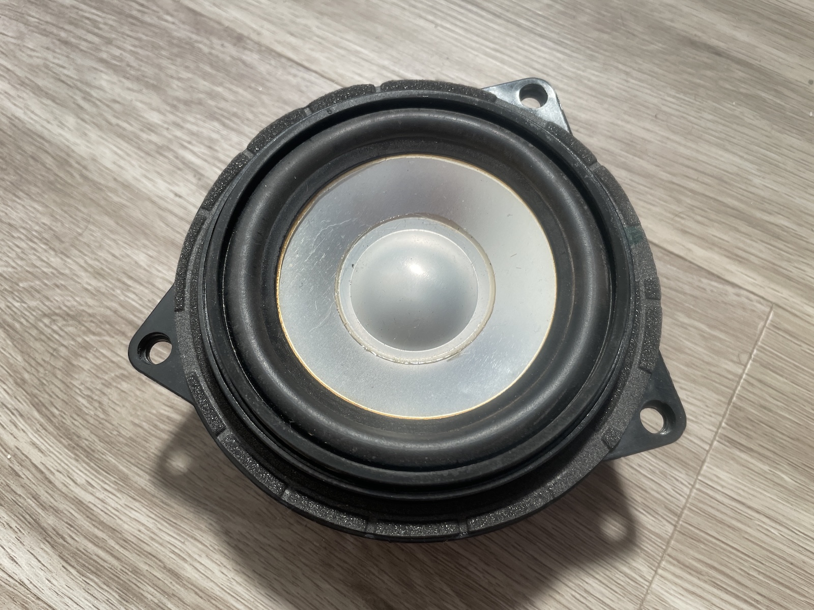 Metallic speaker cones, such as the one on this stock BMW E90 Logic 7 speaker, offer high rigidity but can be prone to resonance.